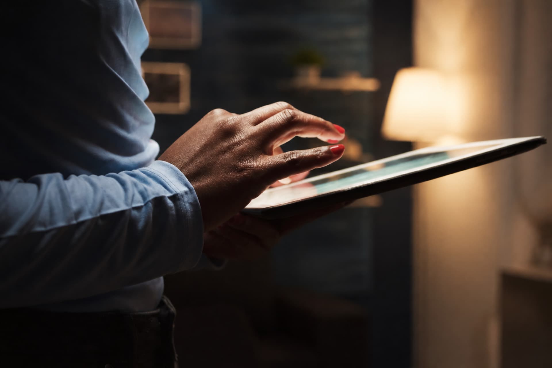 Hands using a tablet in a dimly lit office